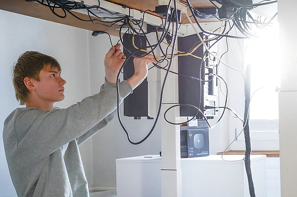 Ein Mitarbeiter sortiert Kabel und Hardware.